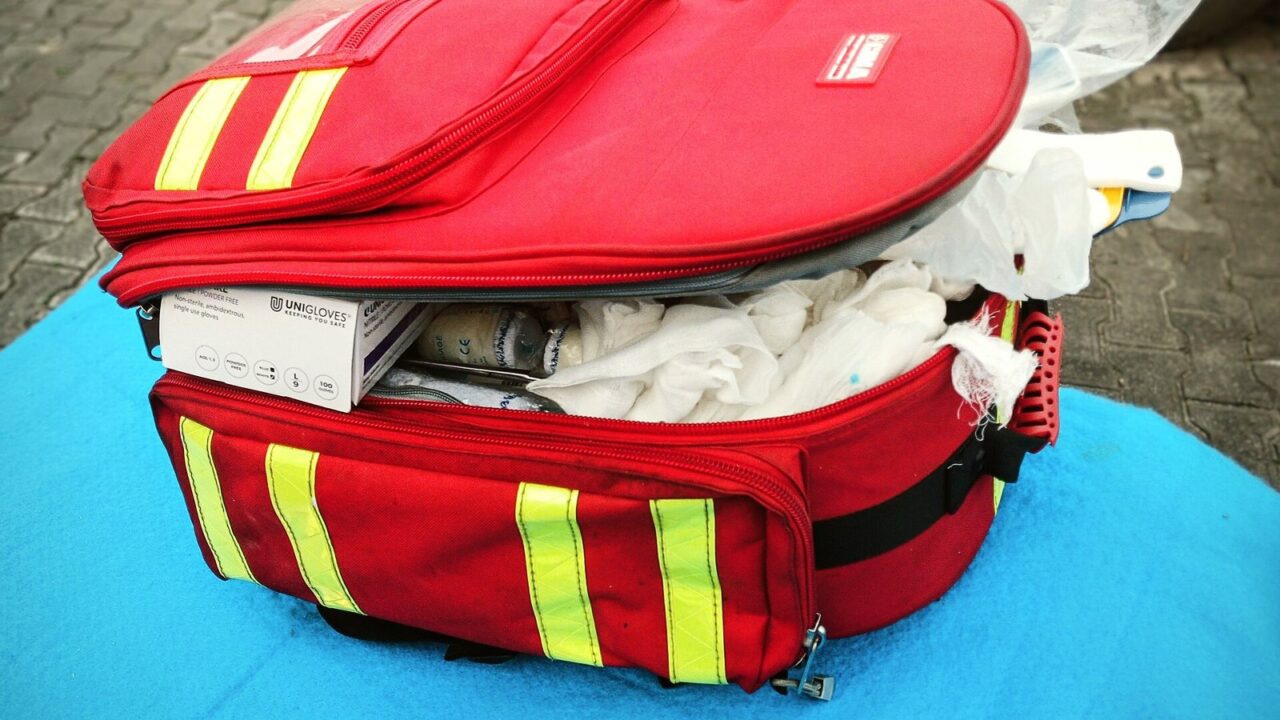 Trousse de premiers secours rouge ouverte contenant gants, pansements et compresses